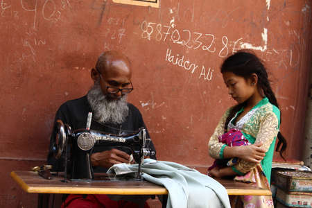 New Delhi, Delhi/ India - June 10 2020: Elderly tailor working with textiles on streets of Delhi.