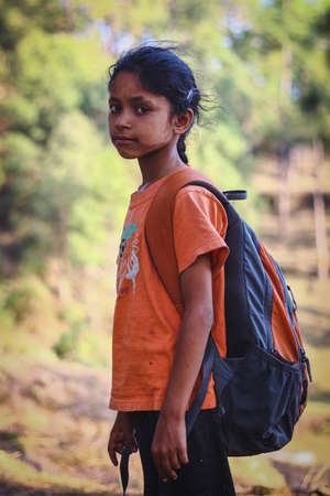 almora, uttrakhand/ india - june 14 2020 : a portrait of a small girl with white marks on her face going to school with a heavy bag.のeditorial素材