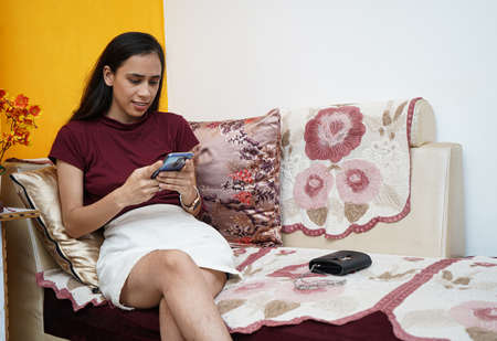 A young beautiful indian girl wearing headphones while working on her laptop, happy and cheerful while working from home.の写真素材