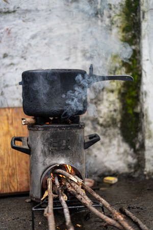 Pressure Cooker kept on top of a modern chulah with wood being burnt.Shallow Depth of field.