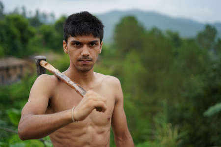 Young handsome shirtless boy holding axe in his hands.の素材 [FY310154719797]