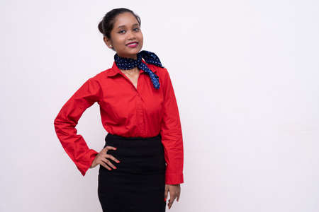 Young charming air hostess in red dress with blue collar posing in front of the camera with white background and copy space.の写真素材