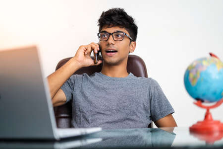 Indian boy talking over phone while working in office.の写真素材