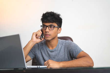 Indian boy talking over phone while working in office.の写真素材