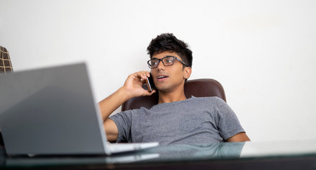 Indian boy talking over phone while working in office.