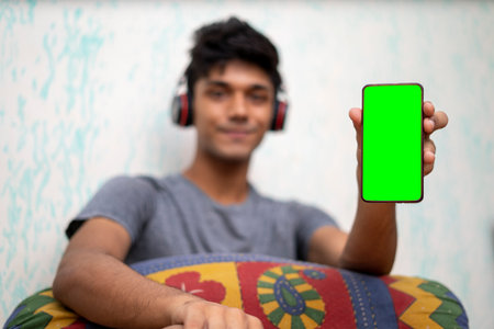Young indian boy holding a phone with green screen.の写真素材