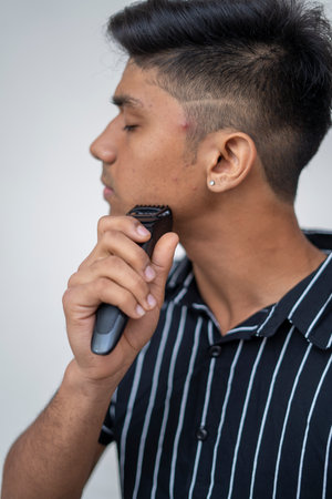 man handsome looks after the skin of the face shaves an electric razor on a white background