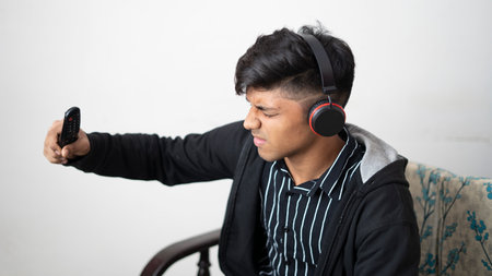 asian man with headphone wearing black jacket holding remote while sad expression face cheering for...
