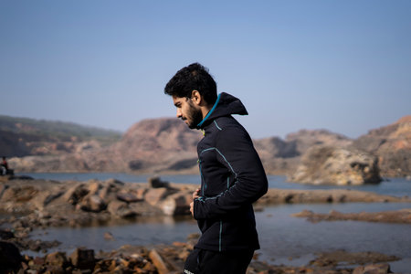 Young Indian fit boy jogging in the morning near a lake situation in middle of a mountain area.の写真素材