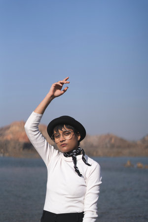 beautiful portrait of an indian girl wearing white dress and a black hat with a black hanky on tied her neck, captured on a white cloth with scenery in background.の写真素材