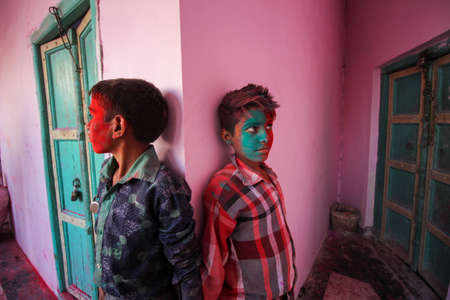 Mathura, Uttar Pradesh, India- January 28 2020: two kids standing in front of a pink wall with their faces covered in colors, enjoying during the festival of holi in mathura.のeditorial素材