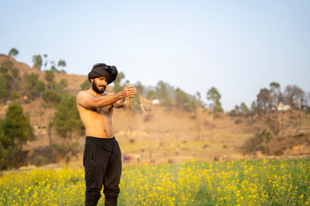Young indian farmer working in the fields, growing crops. Farming and agriculture concept.