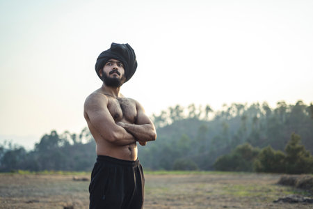 Young indian farmer with a turban standing on a barren field. Crops not growing due to shortage of rain and water.の写真素材