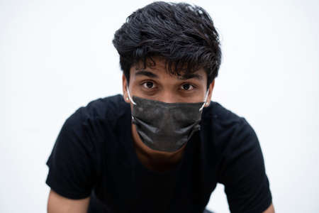 Portrait of a young indian boy wearing a mask, captured in a white isolated background.の写真素材
