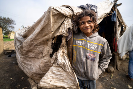 Garh Mukteshwar, Uttar Pradesh- January 13 2022 - A portrait of a female kid smiling into the camera while standing beside her shed home. A poor girl standing beside her home.のeditorial素材