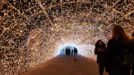 Genoa, Italy - 11/19/2019: Gallery of led lights in red white and orange colors. Low angle view. People enjoying the christmas decorations.のeditorial素材