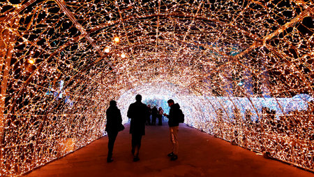 Genoa, Italy - 11/19/2019: Gallery of led lights in red white and orange colors. Low angle view. People enjoying the christmas decorations.のeditorial素材