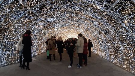 Genoa, Italy - 10/12/2019: An amazing christmas decoration lights on the streets of Genoa in winter with an artistic background and some people enjoing the momentの写真素材