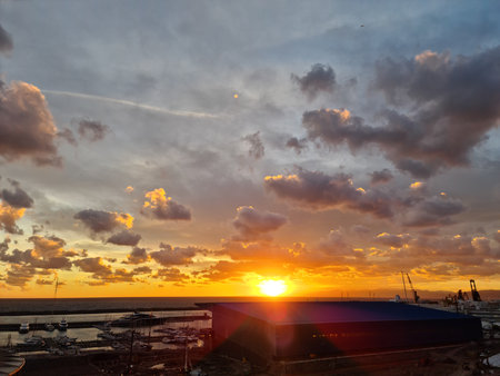 Genova, Italy - January 1, 2021: An amazing photography of the sunset in winter days over the sea and the port of Genova with beautiful red sky and some amazing colored clouds in the background.のeditorial素材