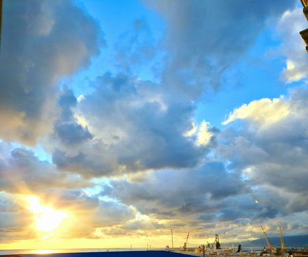Genova, Italy - January 1, 2021: An amazing photography of the sunset in winter days over the sea and the port of Genova with beautiful red sky and some amazing colored clouds in the background.のeditorial素材