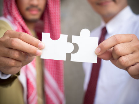 Arab business man holding puzzle with businessman, close up at hand, team work and cooperation conceptの写真素材