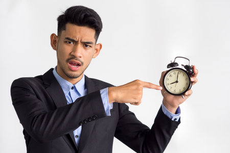 Businessman/boss/manager showing alarm clock on white background, working time, late, punctual concept.の写真素材
