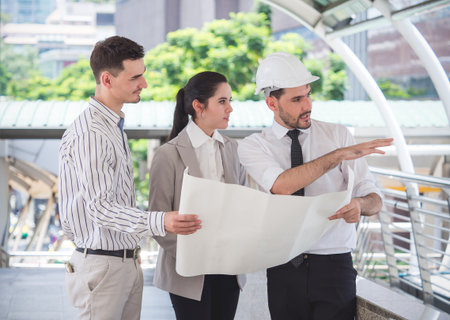 Businessman and businesswoman talking during working online on laptop at outdoor officeの写真素材