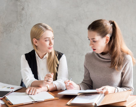 Young caucasian businesswoman discussing with colleague about business plan on tableの写真素材
