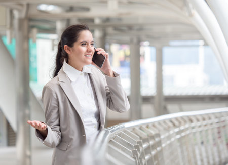 Portrait young caucasian businesswoman 20-30s holding smart phone/cell phone/mobile in formal suit at the modern cityの写真素材