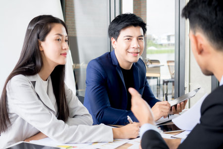 Young asian businessman and Businesswoman discussing in the meeting in office cafe, brain storming for business strategy with happy feeling and smileの写真素材