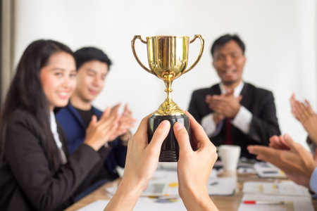 Businessman show thumbs up with trophy, reward, winner, champion and successful for businessの写真素材