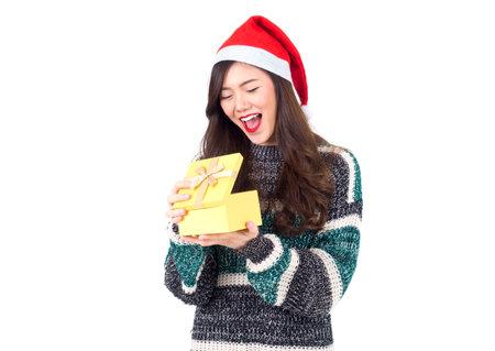Young happy asian woman with santa hat holding gift box present for christmas party and celebration isolated on white background, merry christmas and happy new year conceptの写真素材