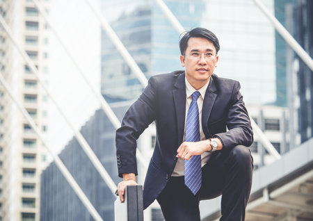 middle age businessman/boss/manger in formal suit sitting in modern city with business bag, start up business conceptの写真素材
