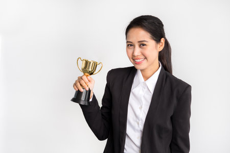 Young asian businesswoman in formal suit holding golden trophy on white background, winner and successful/achievement conceptの写真素材