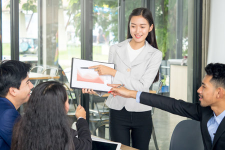 Young asian businesswoman with presentation during business meeting at cafe, financial report, presentation chart, business presentation and teamwork conceptの写真素材