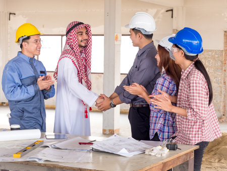 Engineer, architect and arab businessman planing for project construction building, talking and discuss on drawing blueprint plan, working with happy feeling, shaking hands and clapping handsの写真素材