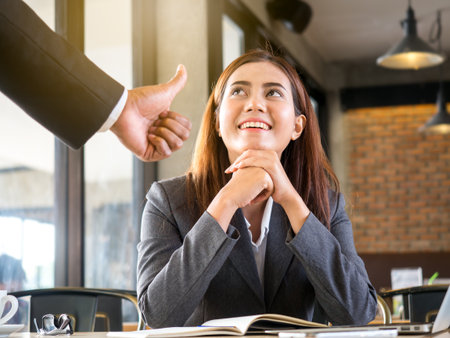 Boss/employer admires to young Asian businesswoman/staff/employee with smiling face for her success and good/best in work.の写真素材