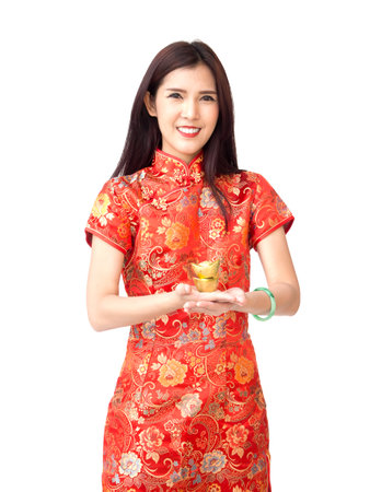 Chinese new year woman concept, isolated asian woman wearing red dress Cheongsam holding gold on handの写真素材