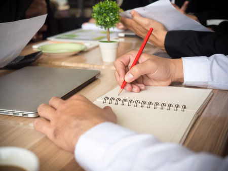 Close up business man honding pencil writing on notebook during meetingの写真素材