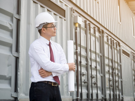 Young asian engineer holding drawing looking at plant. smart engineer for construction work conceptの写真素材