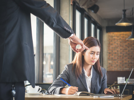 Aggressive/angry boss complaining asian business woman(casual uniform) in cafe officeの写真素材
