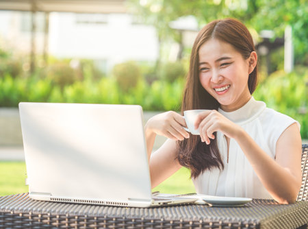 Young beautiful Asian woman working with laptop/internet/online shopping at outdoor park, smile/fresh and happy relaxing feeling in the morning, freelancer working businesswoman lifestyle conceptの写真素材