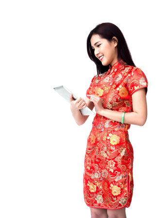 Chinese new year woman concept, isolated asian woman wearing red dress Cheongsam holding tabletの写真素材