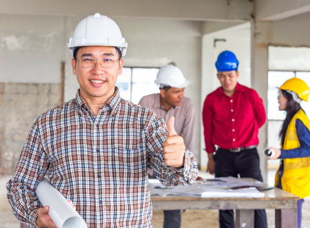 group of engineer/architect/worker man and woman discussing about building plan for construction at job site, working on desk/table with drawing/blueprint/business planの写真素材
