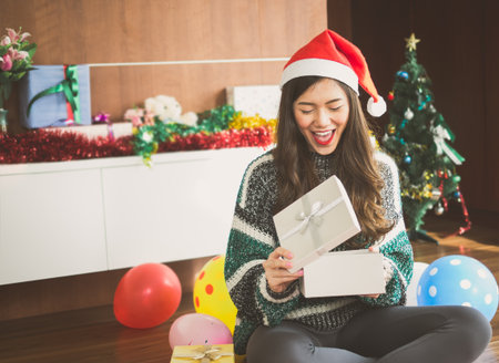 Young happy asian  woman with santa hat surprise and holding gift box present for christmas party and celebration, merry christmas and happy new year conceptの写真素材