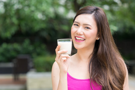 Young beautiful asian woman drinking milk, soy milk outdoor, healthy drinking and food for woman conceptの写真素材