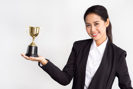 Young asian businesswoman in formal suit holding golden trophy on white background, winner and successful/achievement conceptの写真素材
