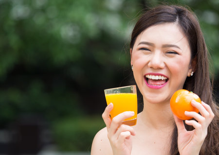Young beautiful asian woman eating/drinking orange/orange juice fruits, healthy eating with clean food and fruit for diet contactの写真素材
