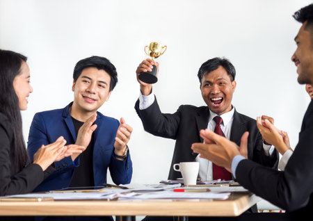 Businessman clapping hands with trophy, reward, winner, champion and successful for businessの写真素材
