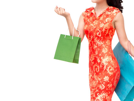 Chinese new year woman concept, isolated asian woman wearing red dress holding shoping bagの写真素材